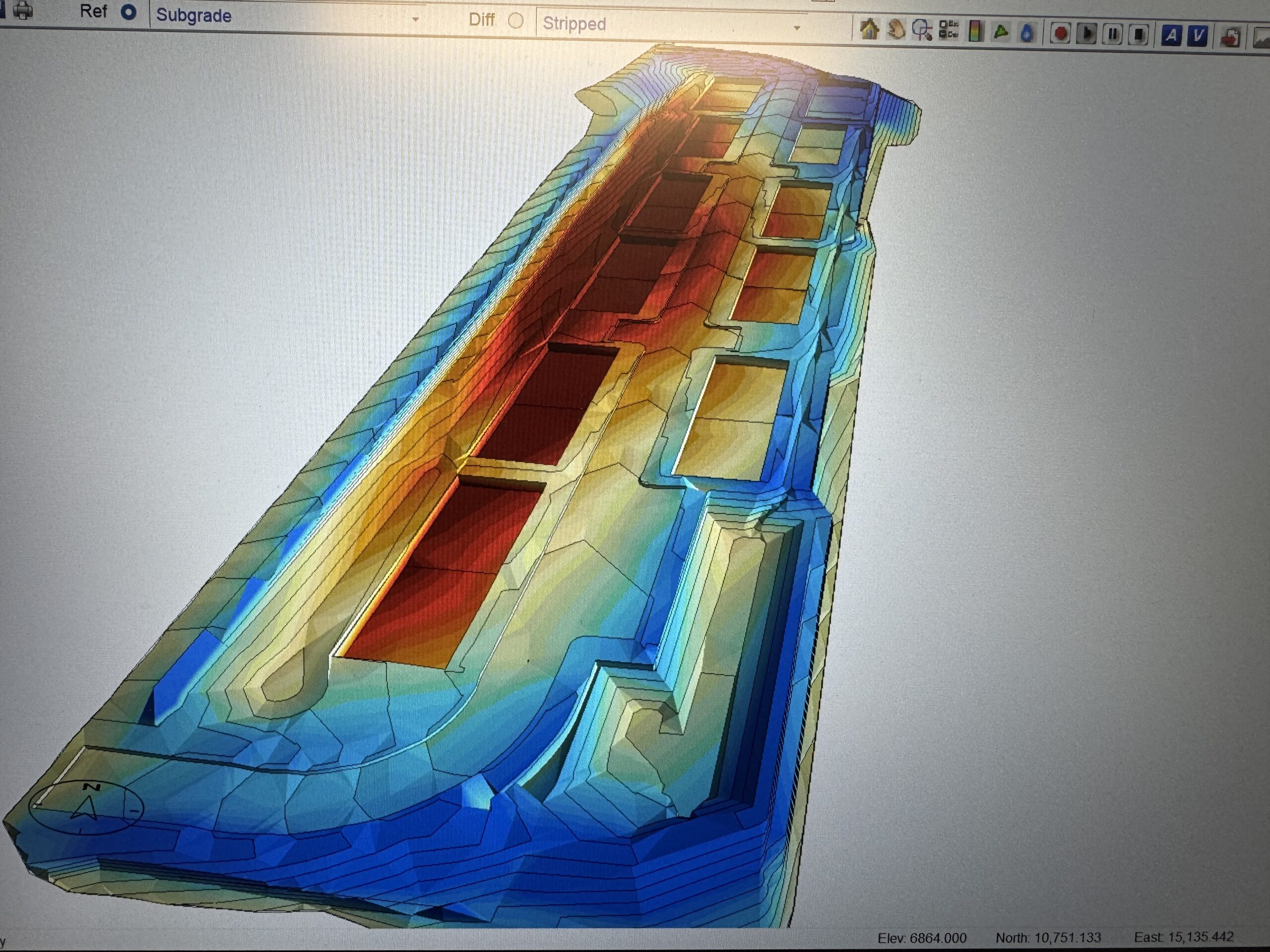Perspective view of a long color-coded earthwork model showing building pads and slopes